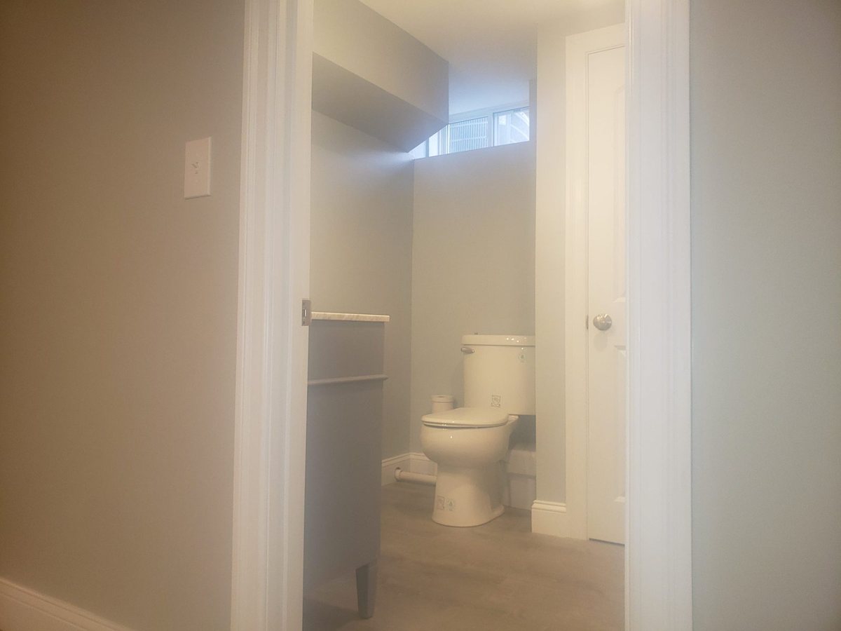Bathroom under renovation with a white toilet, light walls and a small window