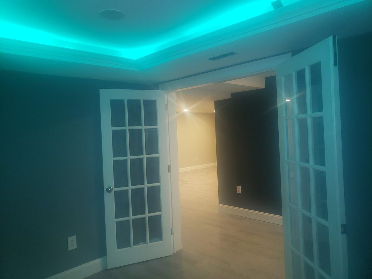 Room with turquoise LED cove lighting and white French doors